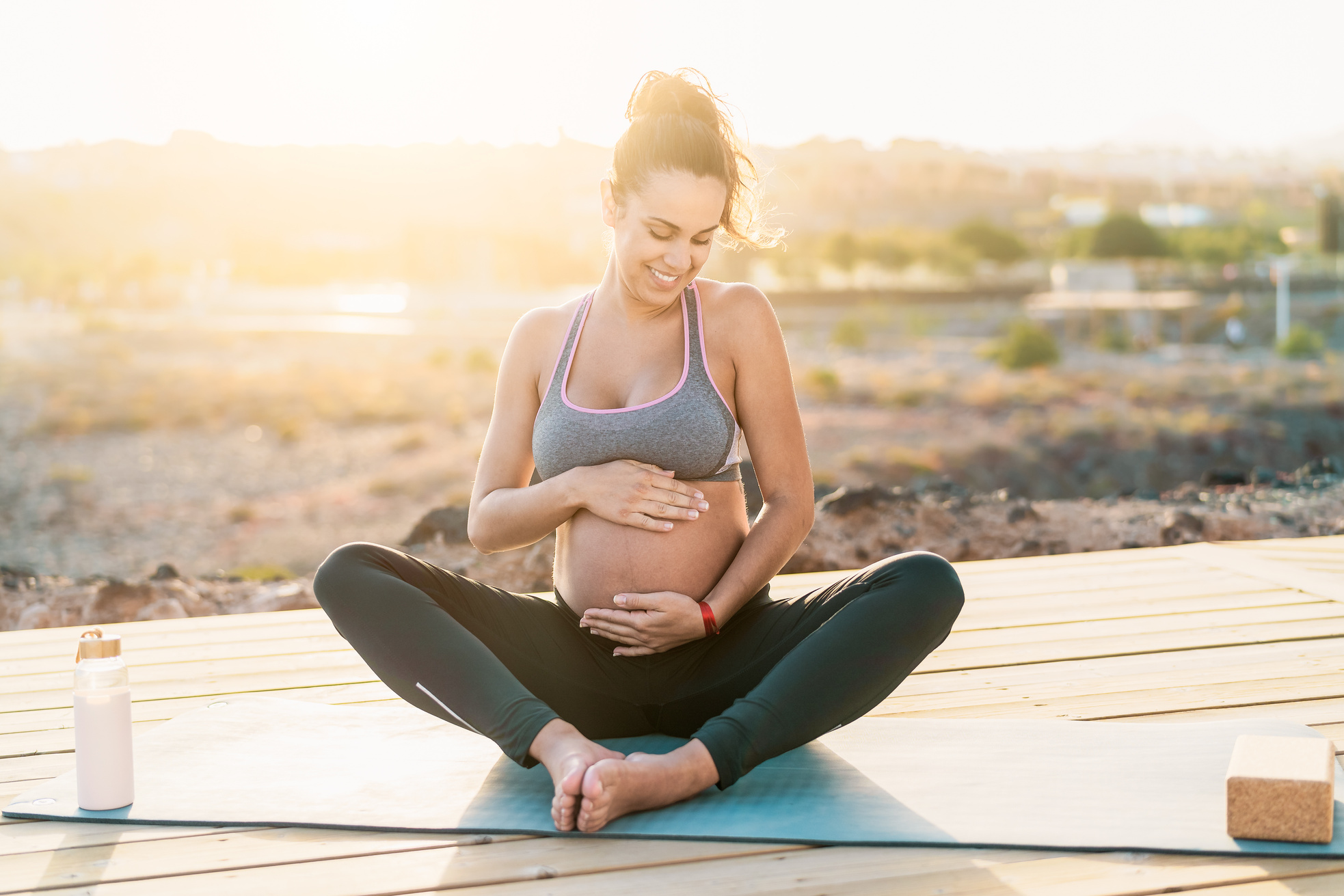 Pregnant Woman Massaging Belly While Exercising Outdoors